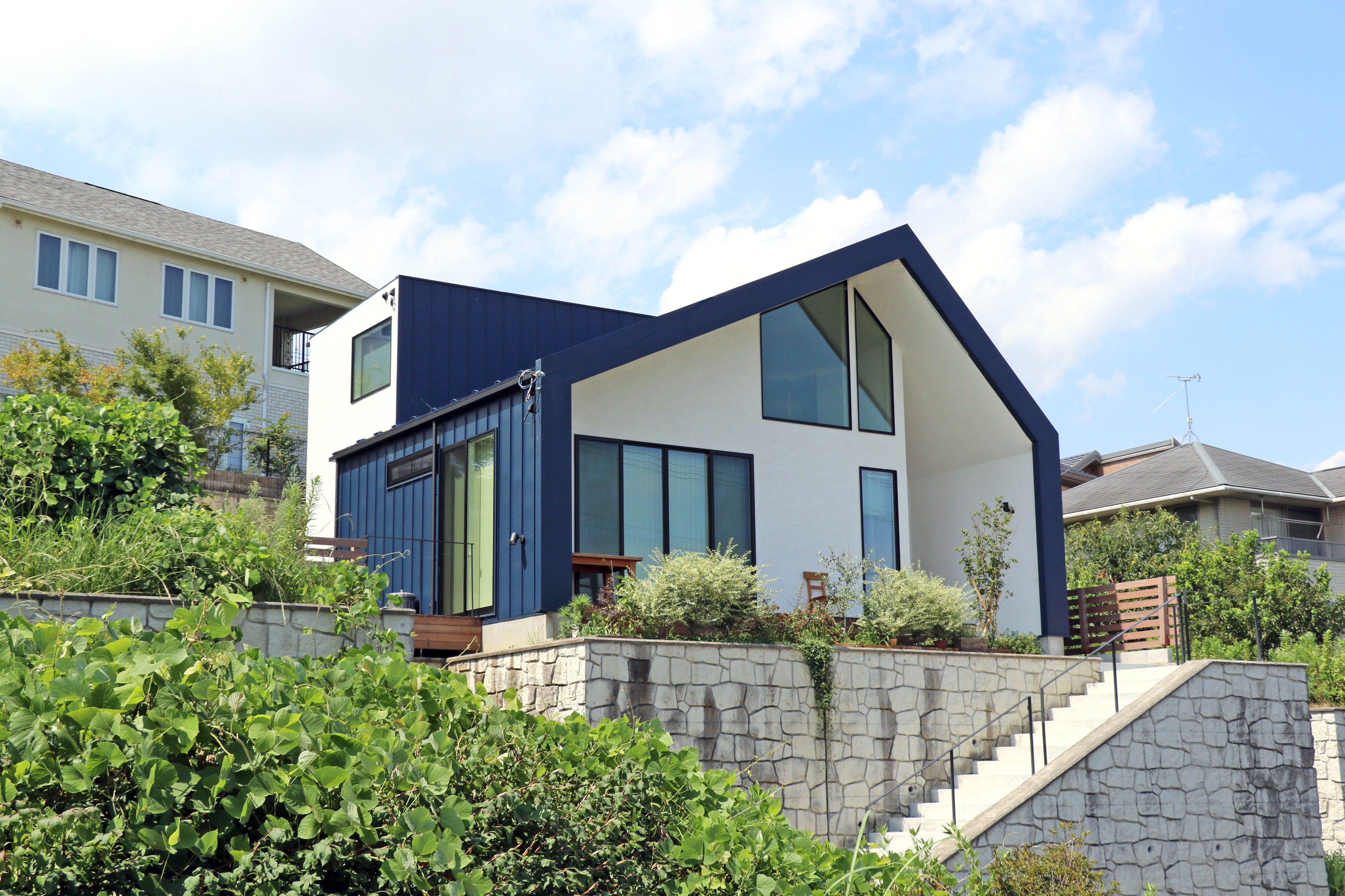 蒼ガルバリウムと白モルタル塗り壁のコントラストが美しい家